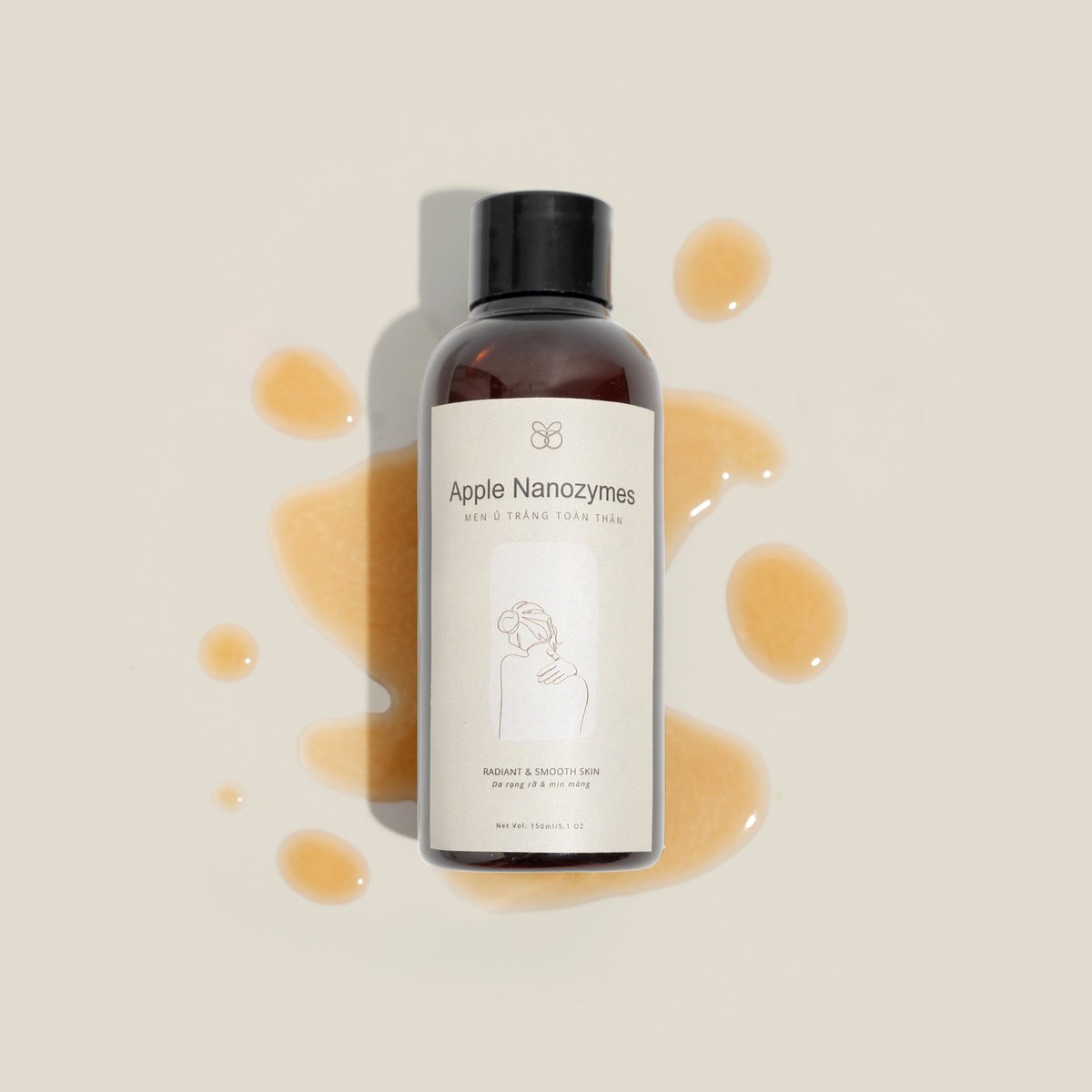 Ảnh tinh chất: chai toner đứng giữa những giọt tinh chất vàng óng trên nền be, chụp tại studio Juva Media